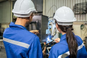Asian male and female industrial worker working in manufacturing plant. Attractive industry factory engineer people wear helmet and processes orders and product at manufactory warehouse with happiness