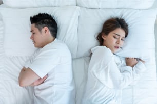 Asiatisches junges Paar liegt auf dem Bett mit schmerzhaftem Streit nach dem Kampf. Neue Ehe Mann und Frau fühlen sich untröstlich für ihren Streitkonflikt und schlafen im Schlafzimmer. Familienproblem-Trennkonzept.