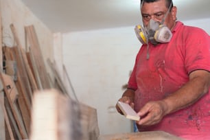 Carpenter with a mask working with wood, close-up.