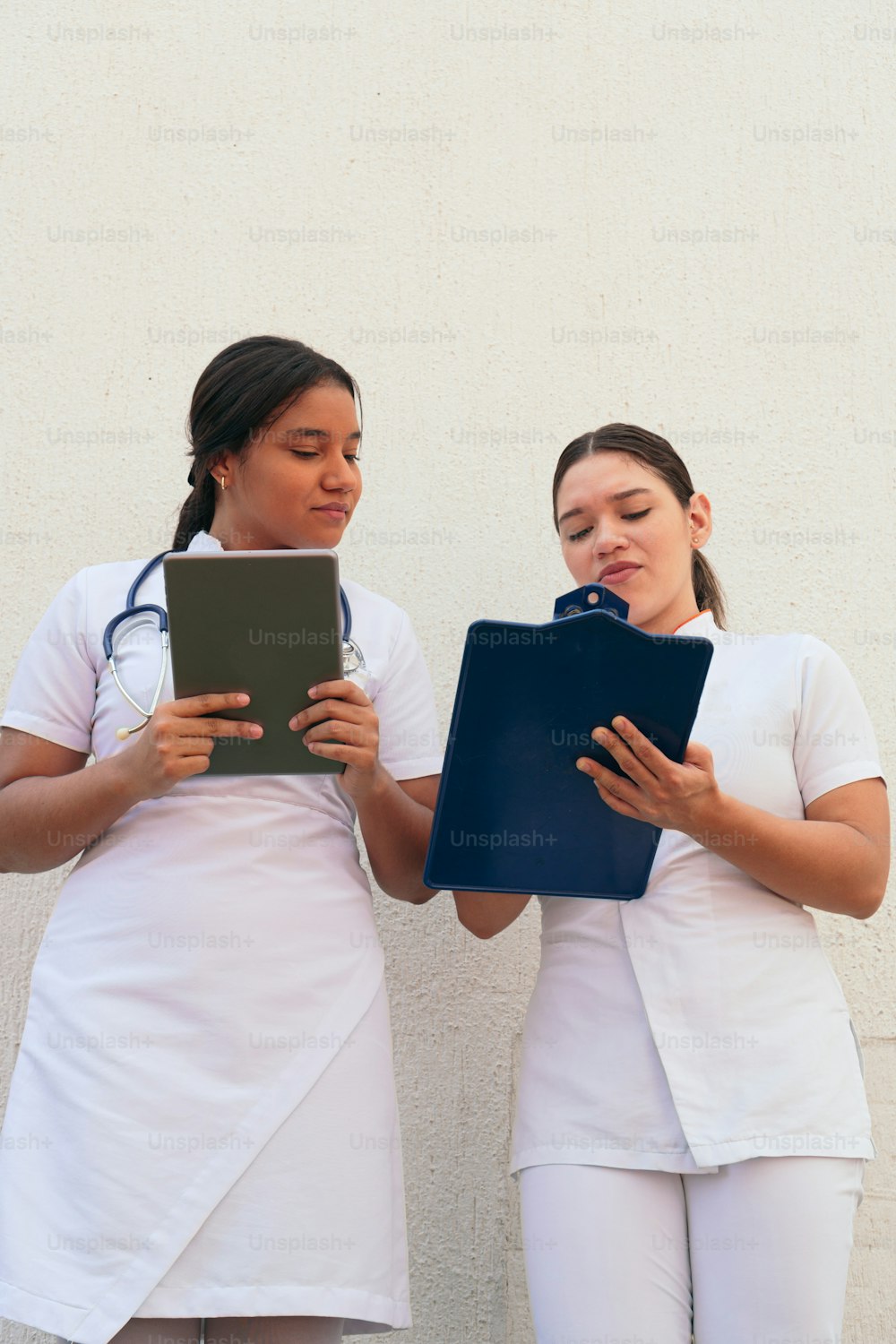 Two female doctors looking at the clipboard while working at the hospital