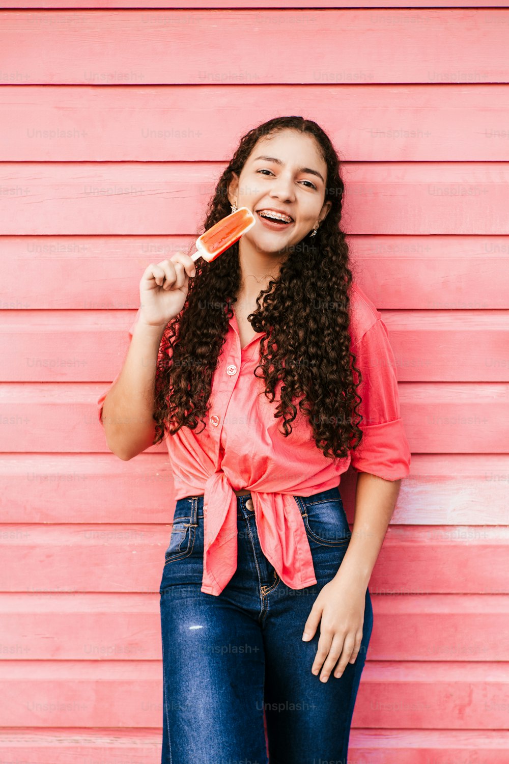 Vertikales Porträt eines lateinamerikanischen Mädchens, das ein Eis am Stiel isst