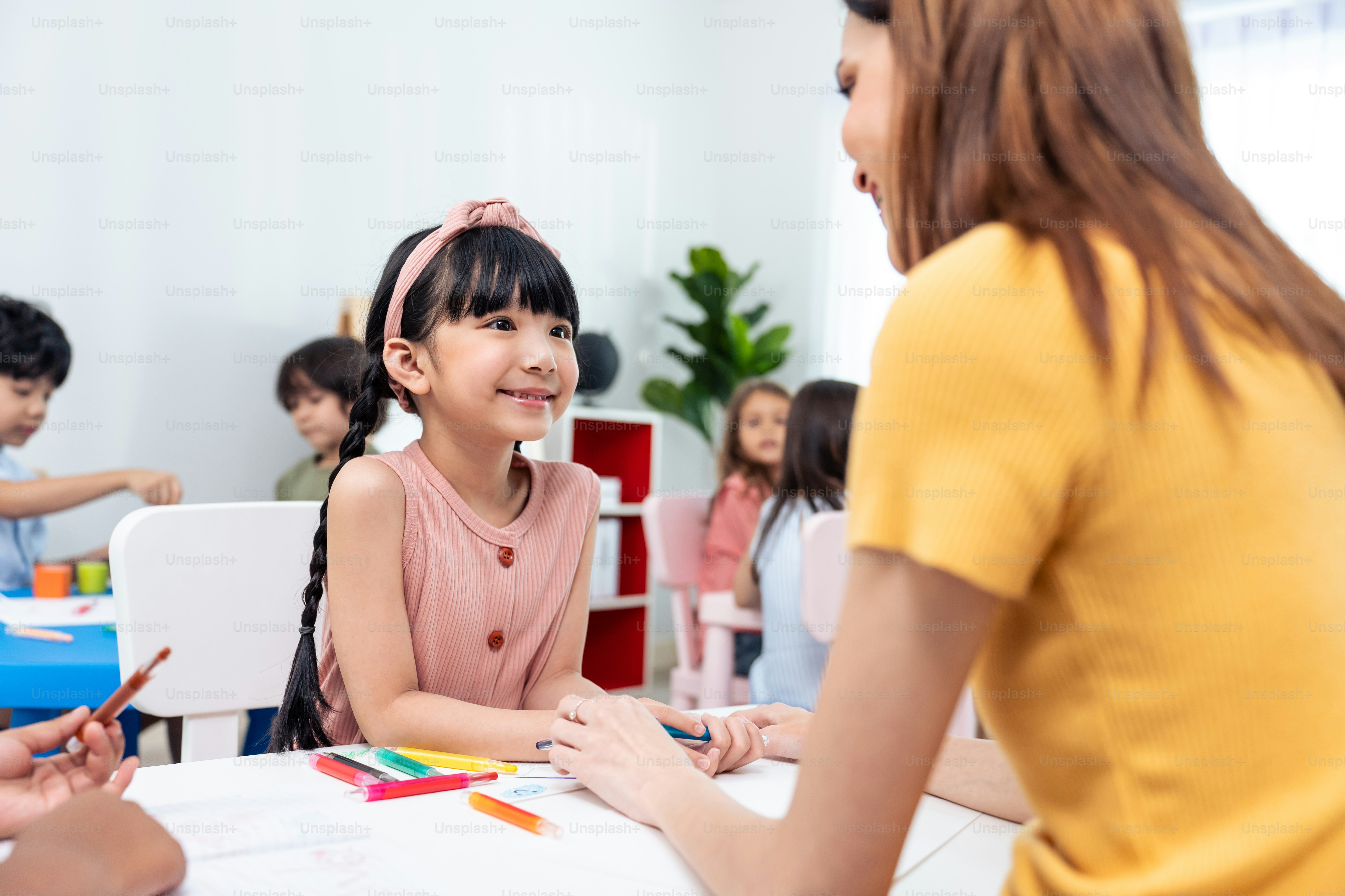 A young girl smiling at her teacher during a classroom art activity