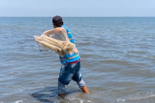 Pescatore che getta una rete in mare