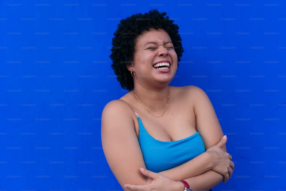 Young Smiling Latin woman looking at camera in front of a blue background