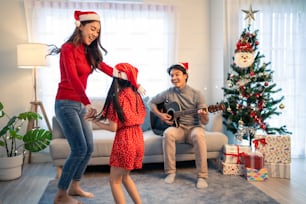 Asian lovely family member enjoy sing Christmas song together at home. Young little daughter feeling happy and excited to celebrate holiday Christmas Thankgiving party together with parents in house.