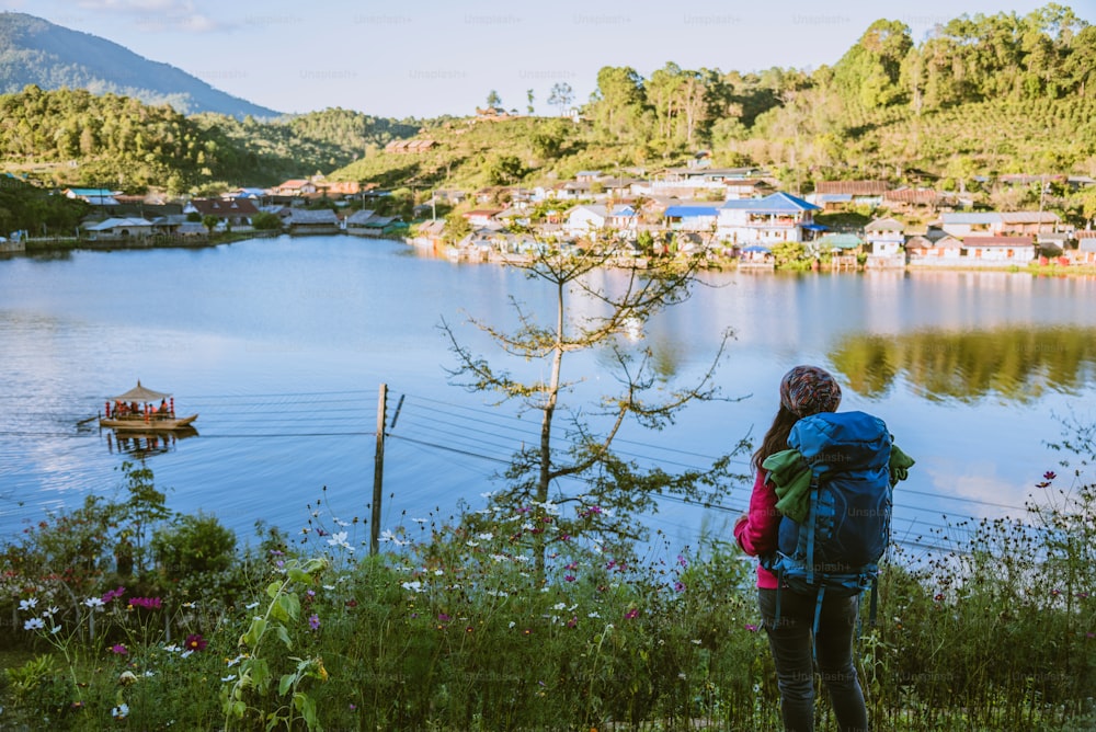 リュックサックを背負った女の子が湖の美しい景色を眺めながら立っています。タイのメーホンソンでの旅行で山に日光を見ている観光客。