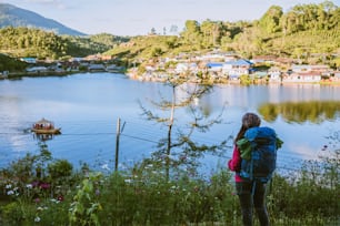 Muchacha con mochila de pie mirando hacia adelante en hermosa vista en el lago. Viajero turista que busca la luz del sol en las montañas en viaje en Mae Hong Son, en Tailandia.