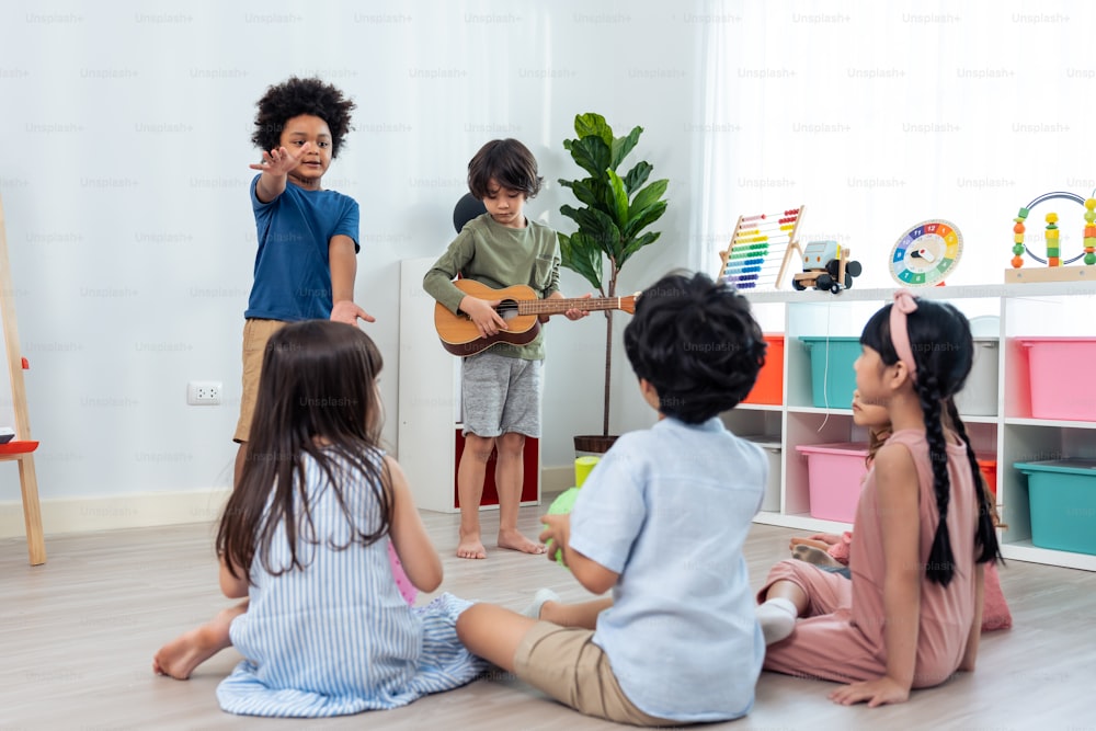 Caucasian beautiful woman teacher doing activity with kids at school. Attractive beautiful Instructor master female singing a song and dancing with student kindergarten preschool together in classroom