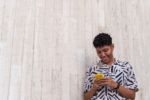 African woman holding a smartphone and looking at it while standing street