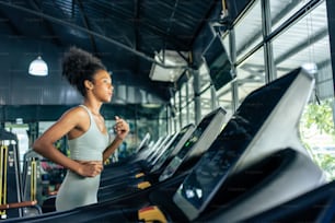 아프리카 계 미국인 젊은 스포츠우먼은 체육관에서 러닝 머신에서 달리기로 운동합니다. . 매력적인 아름다운 운동 선수 소녀는 피트니스 경기장에서 건강 웰빙을 위해 근육을 유지하고 칼로리를 태우는 운동을 연습합니다.