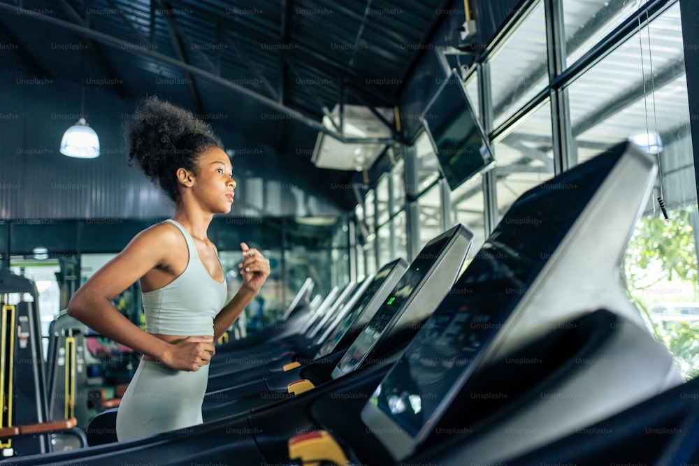 African American young sportswoman exercise by run on treadmill in gym. . Attractive beautiful athlete girl practice workout to maintain muscle and burn calorie for health wellbeing in fitness stadium