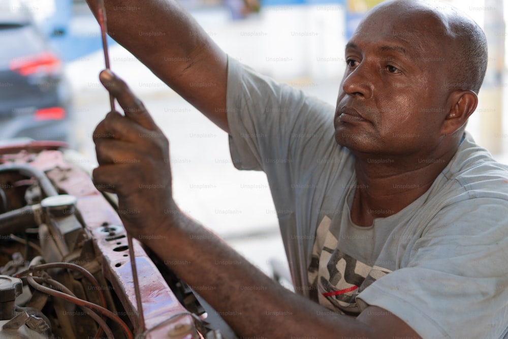 Male mechanic working on a vehicle at a car service station. Technician in car repair shop.
