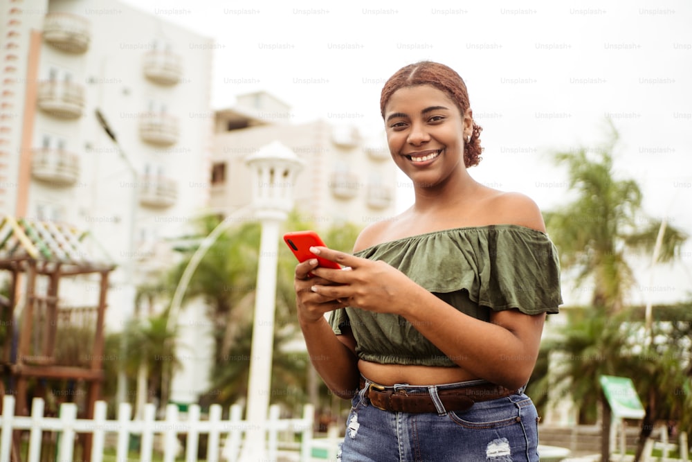 야외에서 휴대폰을 사용하는 젊은 흑인 여성. 인터넷 통신 개념입니다.