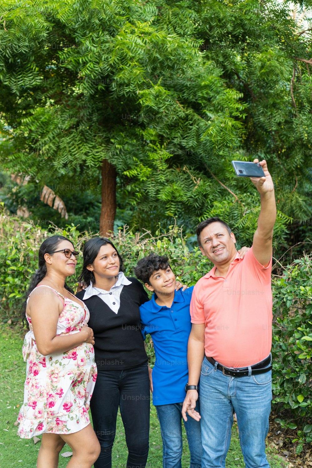 Eine Familie mit zwei Teenagern benutzt ein Handy, um ein Selfie zu machen