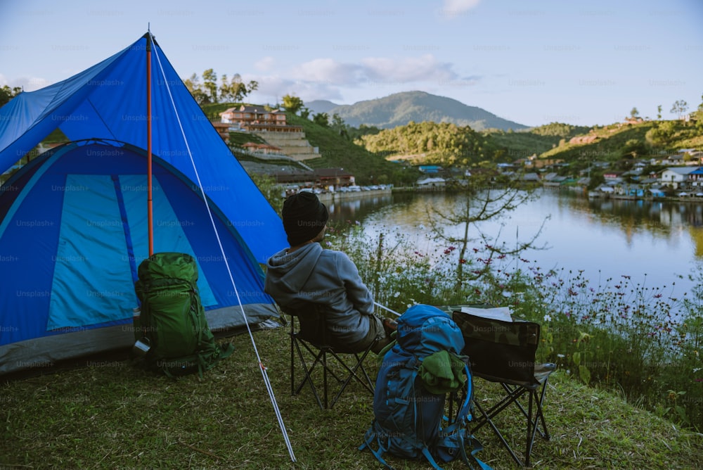 아시아 남자는 자연을 여행합니다. 여행 휴식, 호수 근처의 산에있는 시골 마을에서 캠핑.