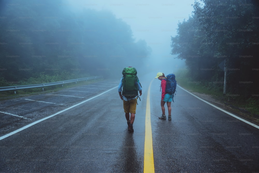 Homem asiático amante e mulheres asiáticas viajam pela natureza. Caminhe na rota da estrada. viajando pela natureza feliz. Em meio à névoa chuvosa. na estação chuvosa.