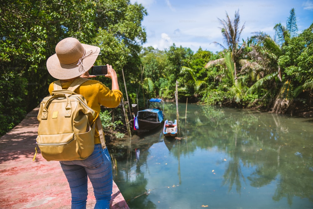 La mujer asiática viaja a la naturaleza. Viaja relájate. Usando el teléfono móvil Tome una foto de barco hermosa naturaleza en tha pom-klong-song-nam. Krabi, Viajes Tailandia.