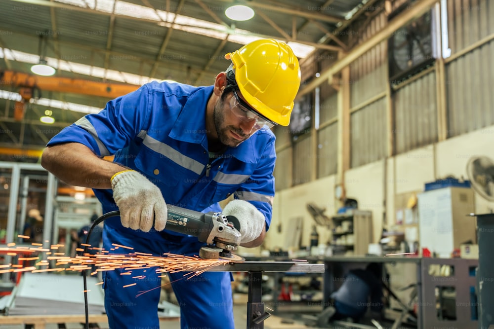白人のハンサムな男性の産業労働者は製造工場で働いています。魅力的な若い男の企業の工場エンジニアは、ヘルメットと保護眼鏡を着用し、製造所の倉庫で鋼を溶接します。