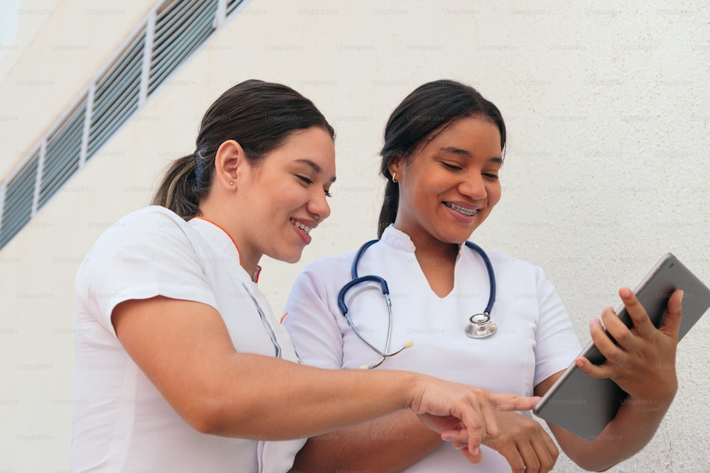 Hispanische Ärztinnen diskutieren beim Blick auf das digitale Tablet