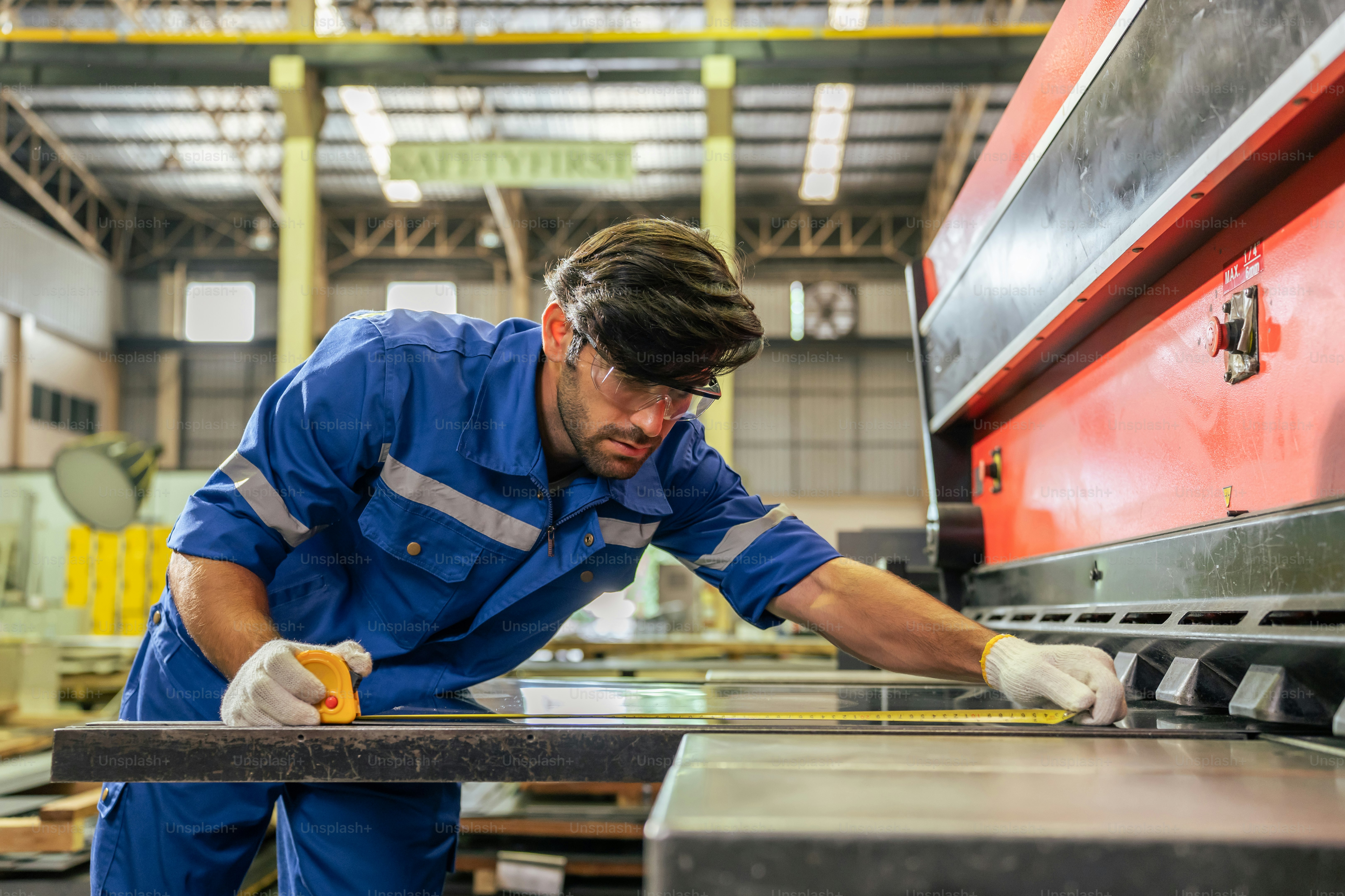 Caucasian handsome male industrial worker work in manufacturing plant. Attractive young man industry factory engineer wear helmet and processes orders and product at manufacturing plant with happiness