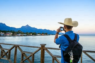 Ein reisender Tourist, der bei Sonnenaufgang ein Foto von den Bergen und dem Meer in der Stadt La Ceiba, Honduras, macht. Reise- und Tourismuskonzept.