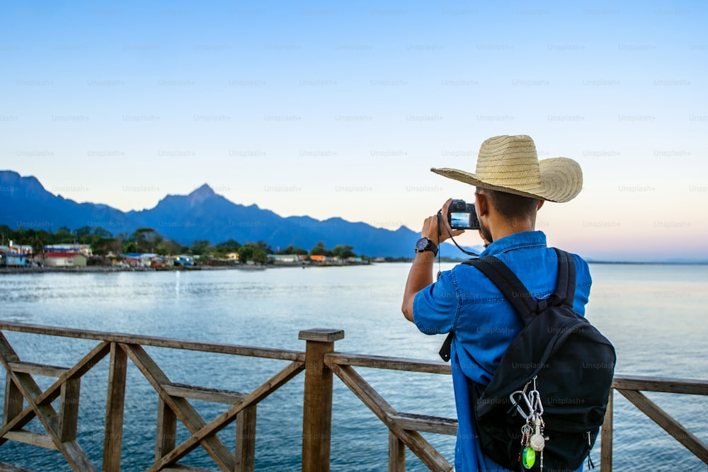 A traveling tourist taking a photograph at sunrise of the mountains and sea in the city of La Ceiba, Honduras. travel and tourism concept.
