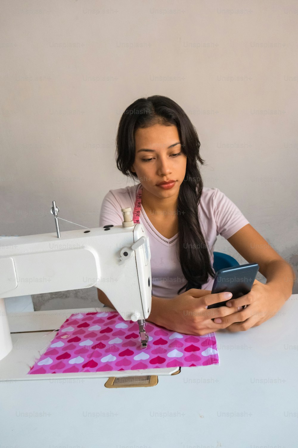 A charming young woman who uses her smartphone while working in the tailor's shop.