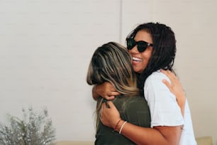 Two friends hugging, smiling and having fun at home.