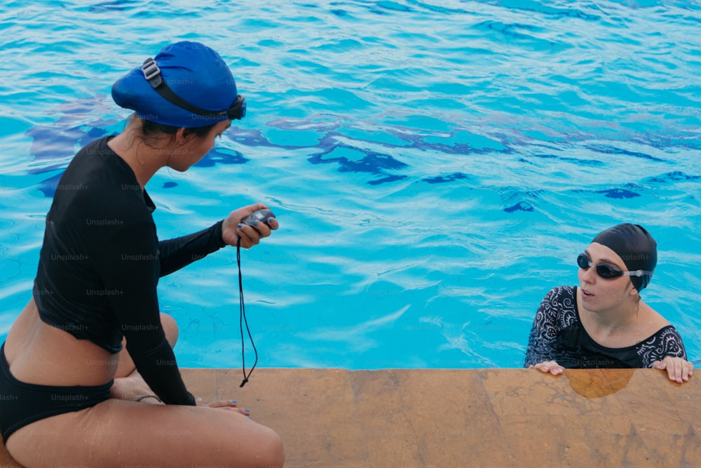 Personal trainer che registra il tempo sul cronometro a bordo piscina durante l'allenamento sportivo