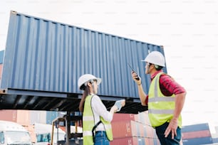 Asian foreman control loading Containers box and staff woman checking container box on forklift for Logistic Import Export in dock