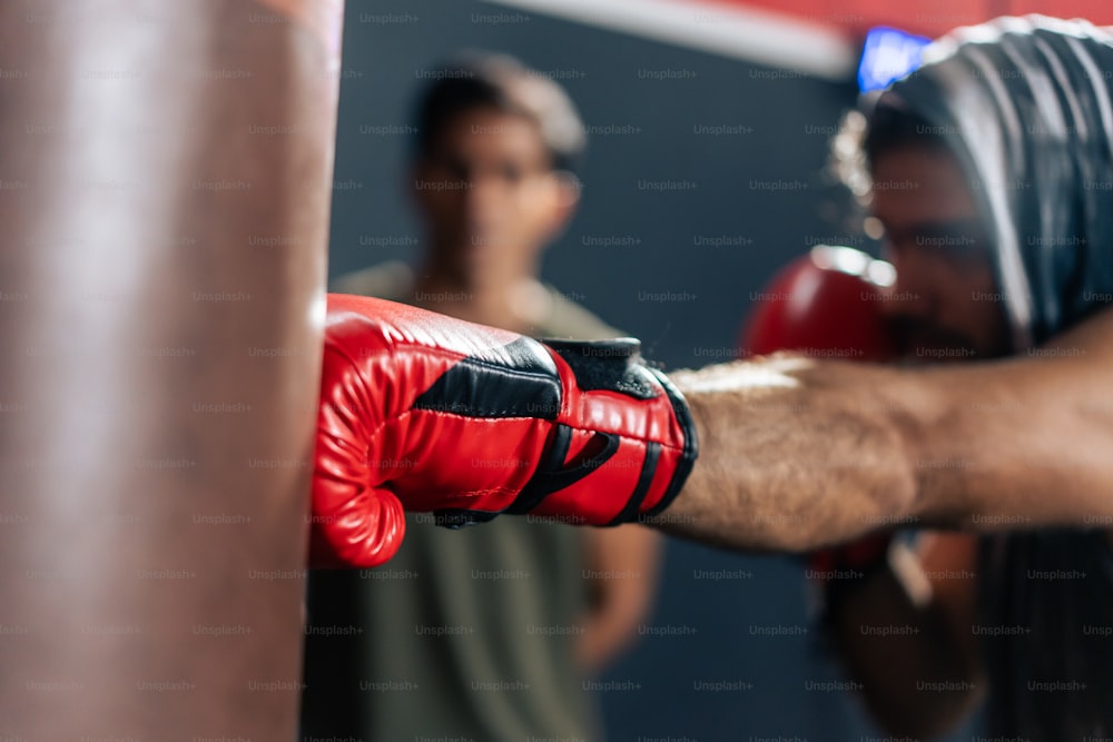 Un homme caucasien porte des gants de boxe avec un entraîneur dans le gymnase. Séduisant jeune bodybuilder boxeur masculin s’entraînant avec l’aide du bel entraîneur Asain pour les soins de santé dans le finess ou le gymnase.