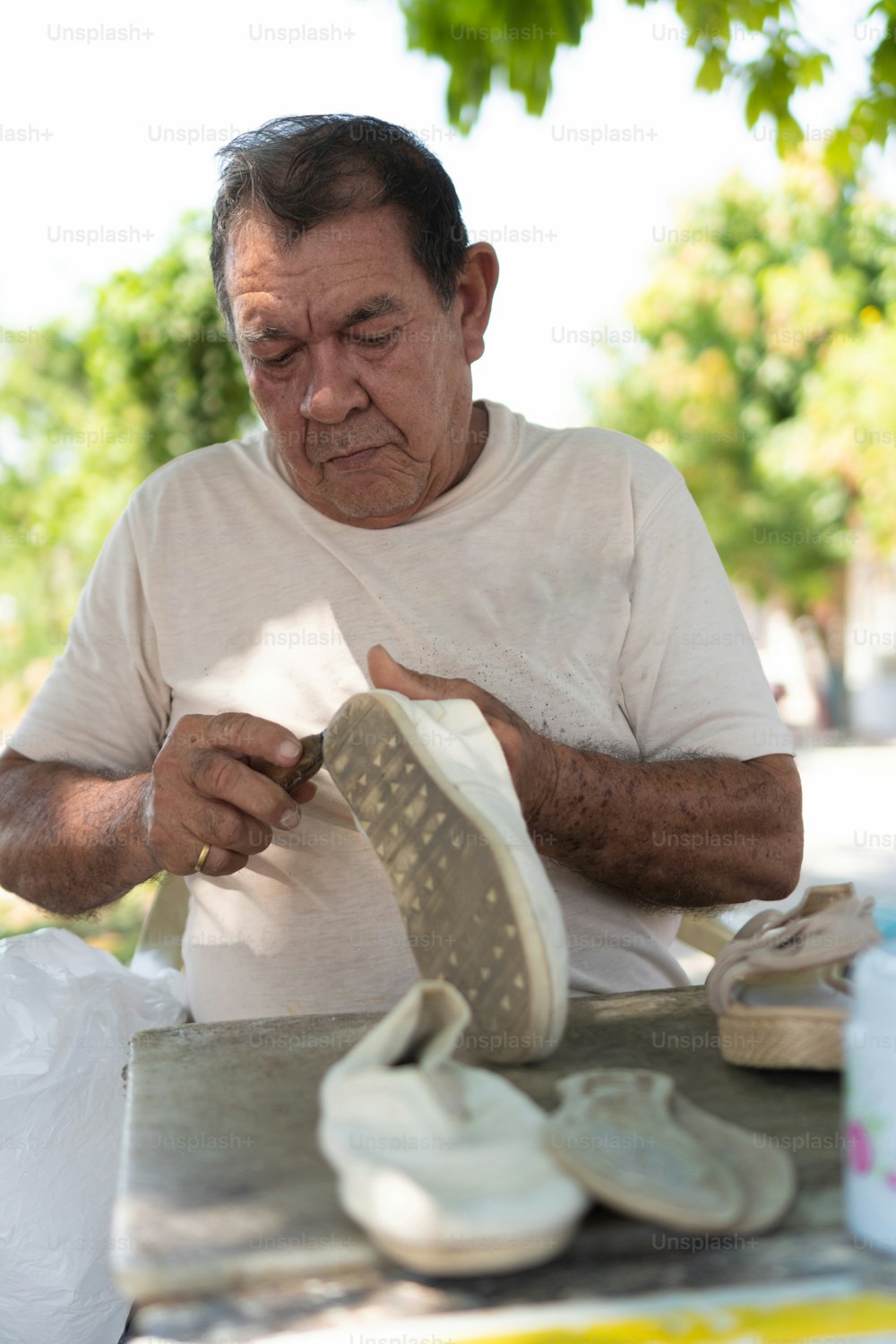 mature man mending shoes in the open air