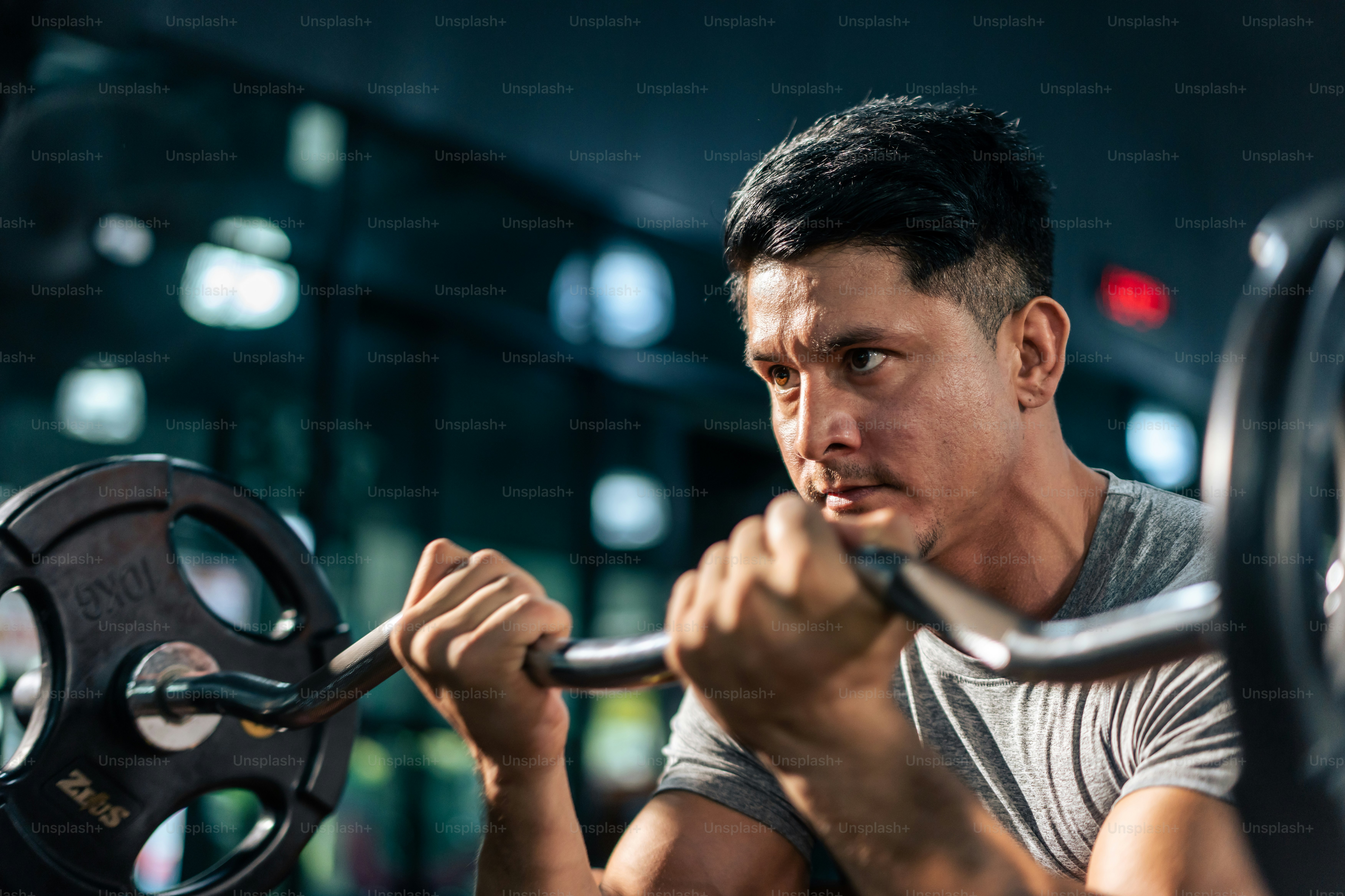 Caucasian sportsman slowly lift up weight machine barbell in stadium.  Active fitness trainer or athlete bodybuilder male working out, training exercise to maintain muscle for health care at gym club.