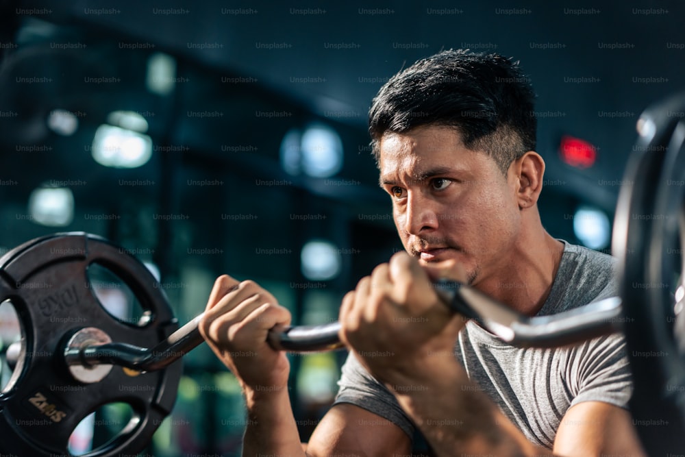 Kaukasischer Sportler hebt langsam die Hantel der Gewichtsmaschine im Stadion an.  Aktiver Fitnesstrainer oder Athlet Bodybuilder männliches Training, Trainingsübung zur Erhaltung der Muskeln für die Gesundheitsversorgung im Fitnessstudio.
