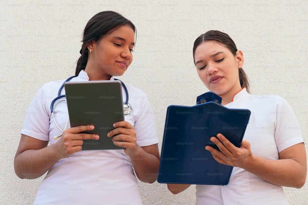 Zwei Latina-Krankenschwestern schauen auf das Klemmbrett, während sie im Krankenhaus arbeiten