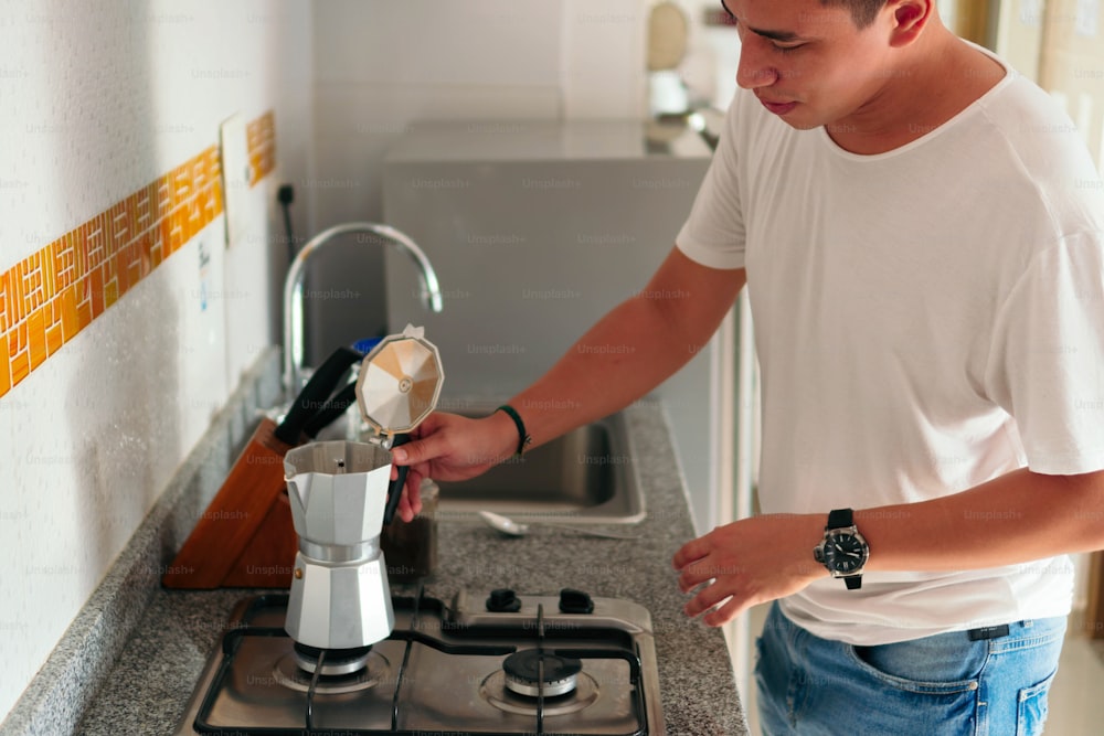 Man preparing a cup of coffee in the kitchen of his house.