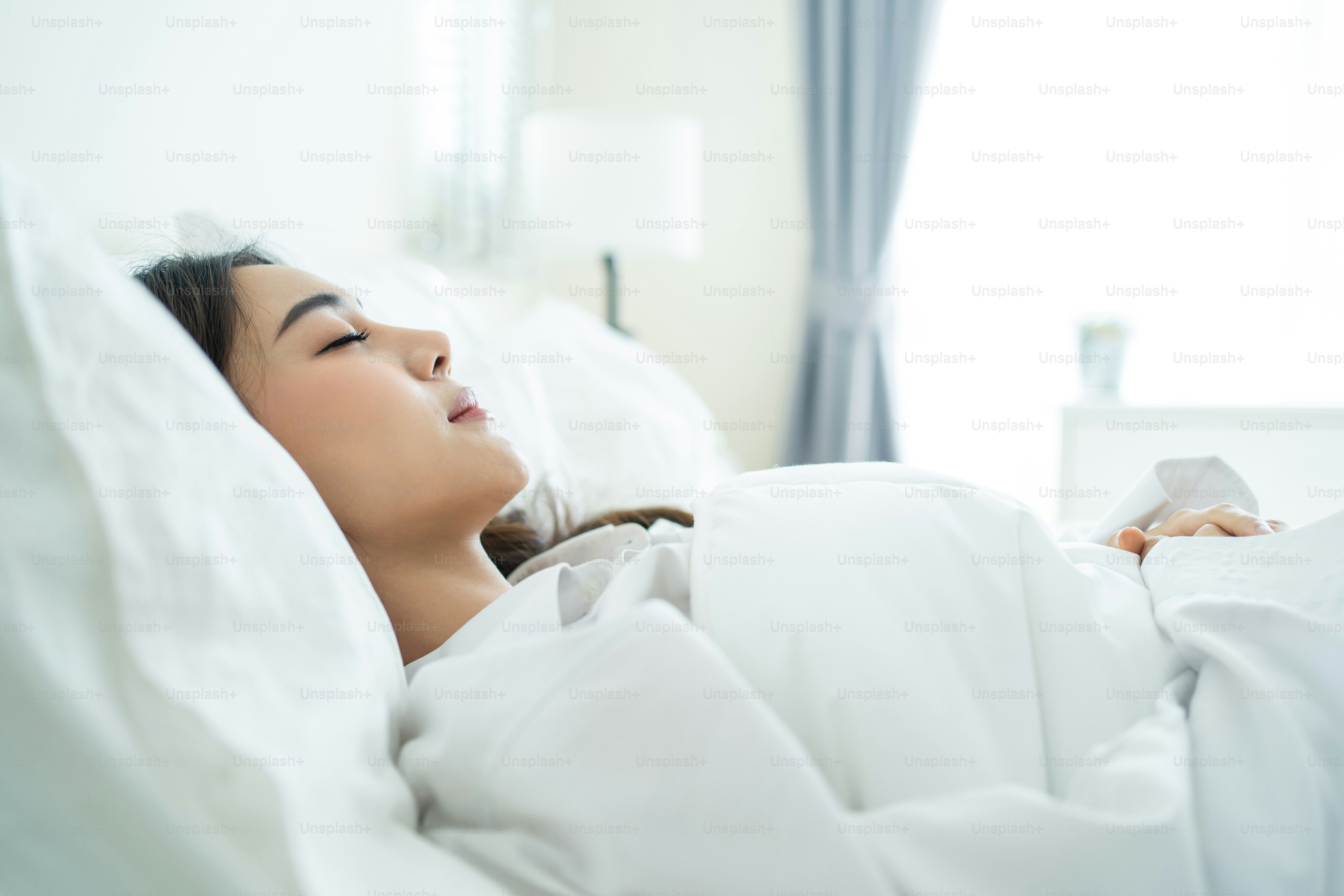 Bella ragazza asiatica in pigiama alzarsi dal sonno in camera da letto. La giovane donna attraente sdraiata sul letto si sente felice con un cuscino e una coperta accoglienti si divertono la mattina presto dopo essersi svegliati in camera a casa