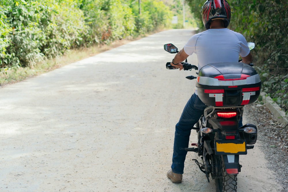 Homme garé avec sa moto le long d’une route de campagne