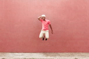 fun black young man jumping over colorful wall of the street.