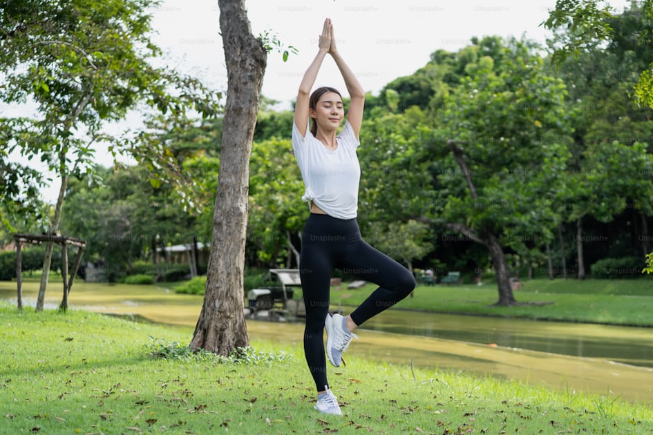 Joven hermosa mujer asiática en ropa deportiva haciendo yoga al aire libre  en el parque por la mañana con luz solar cálida para un estilo de vida  saludable. mujer joven, yogui, hacer