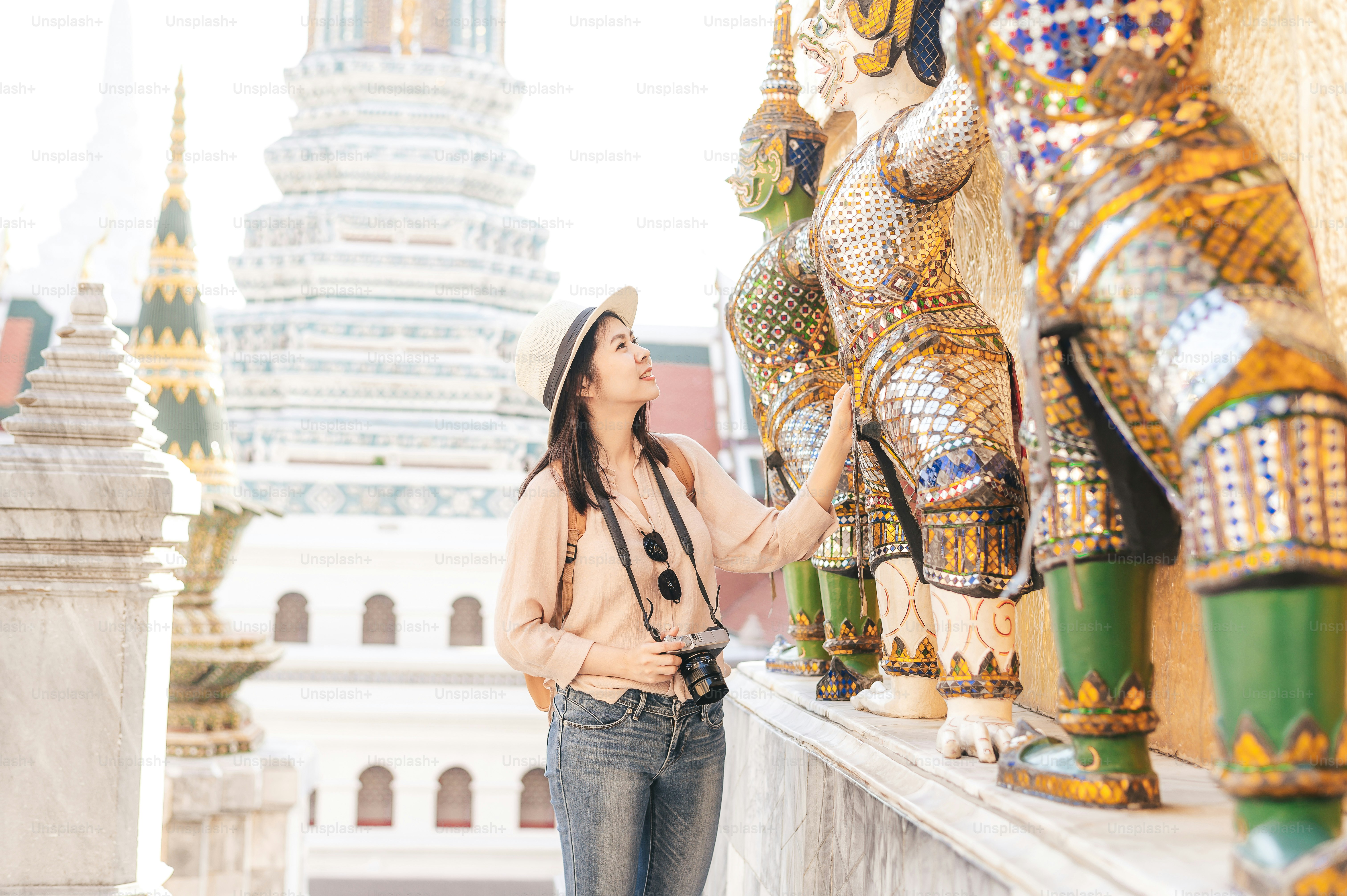Tourist Asian woman enjoy sightseeing while travel in temple of the emerald buddha, Wat Phra Kaew, popular tourist place in Bangkok, Thailand