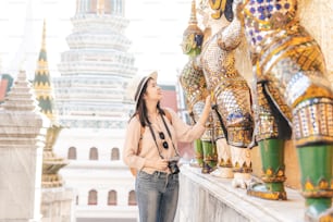 Tourist Asian woman enjoy sightseeing while travel in temple of the emerald buddha, Wat Phra Kaew, popular tourist place in Bangkok, Thailand