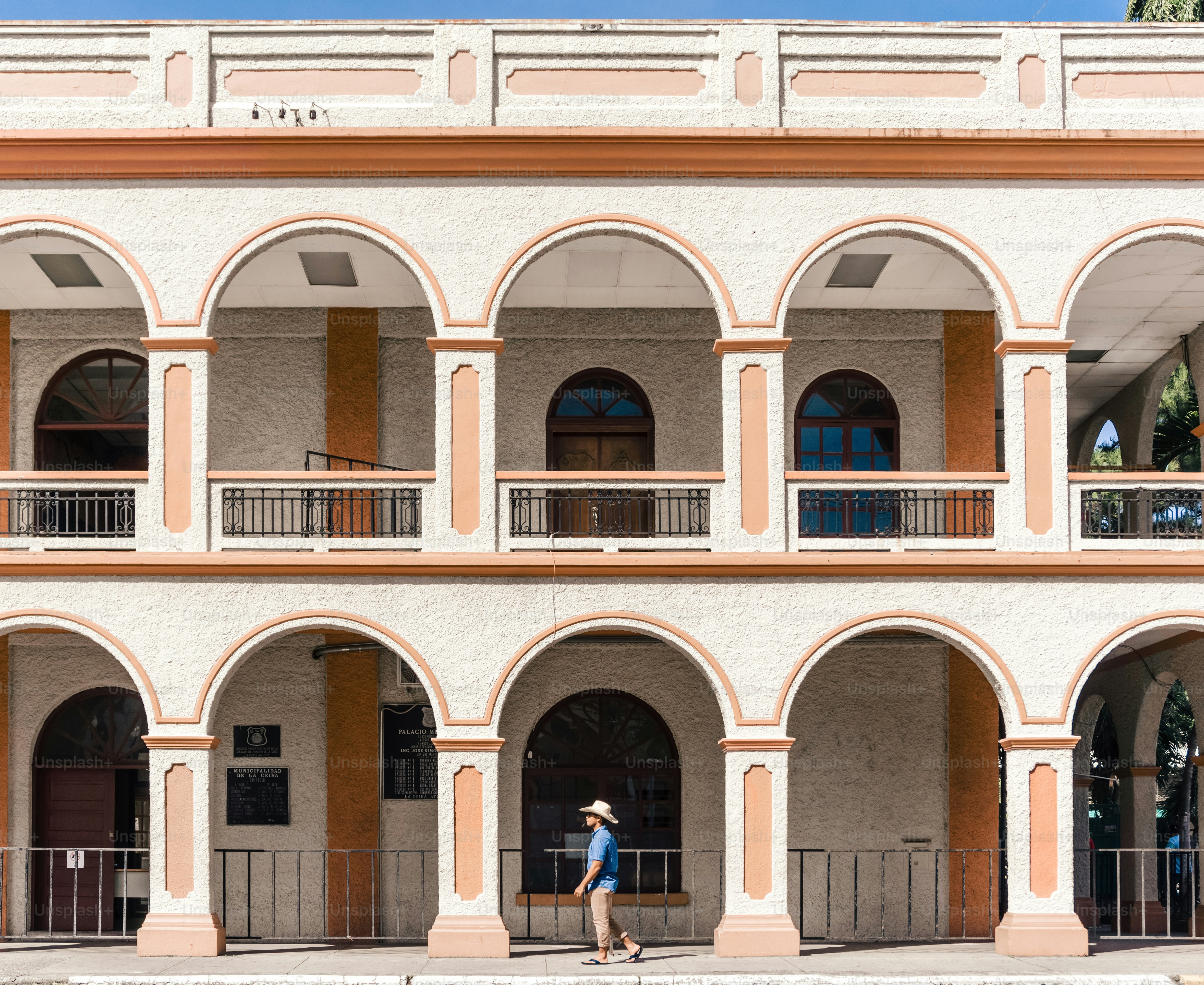 Tourist man with blue shirt and hat walking in front of the municipality of La Ceiba, Atlantida, Honduras.