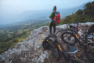 Asian women Travel photograph Nature. Travel relax ride a bike Wilderness in the wild. Standing on a rocky cliff. Thailand