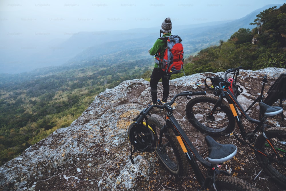 アジアの女性旅行写真自然。旅行、リラックス、自転車に乗る、野生の荒野。岩だらけの崖の上に立っている。タイ