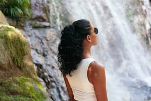Junge Frau am Fuße eines tropischen Wasserfalls. Urlaubskonzept