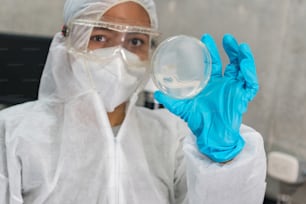 Hispanic scientist holding a petri dish in the science lab. Portrait of health care and the medical concept