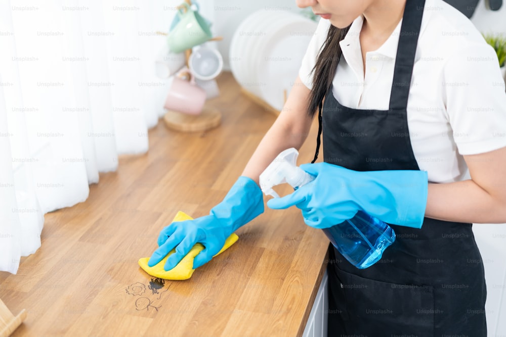 Close up hands of cleaning service woman worker clean kitchen at home. Beautiful young girl housekeeper cleaner feel happy and wiping messy dirty cooking counter for housekeeping housework or chores.