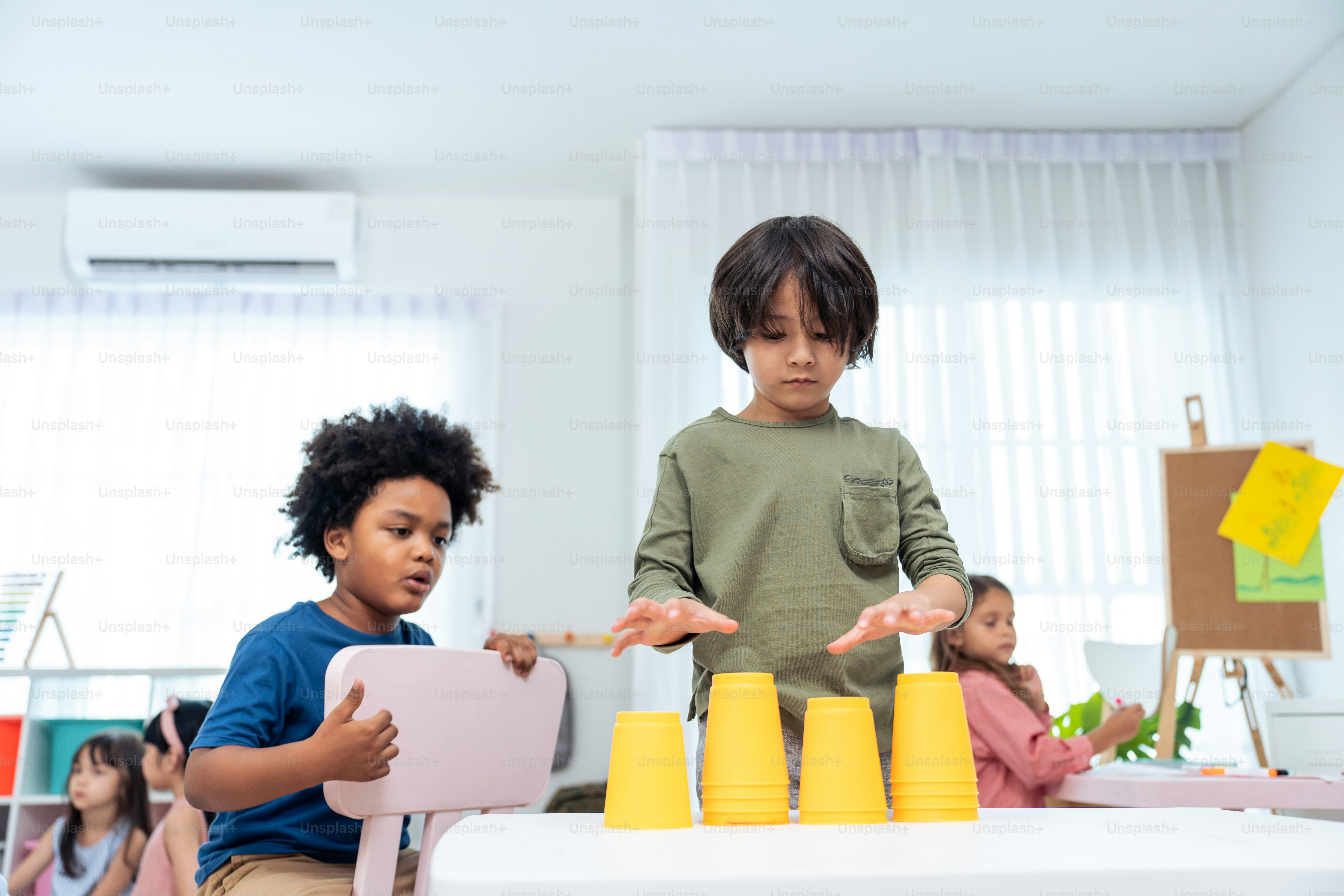 Mixed race Group of young children student playing together in school. Little preschool boy and girl kid feeling happy and fun while spend free time play toys during break in classroom at kindergarten