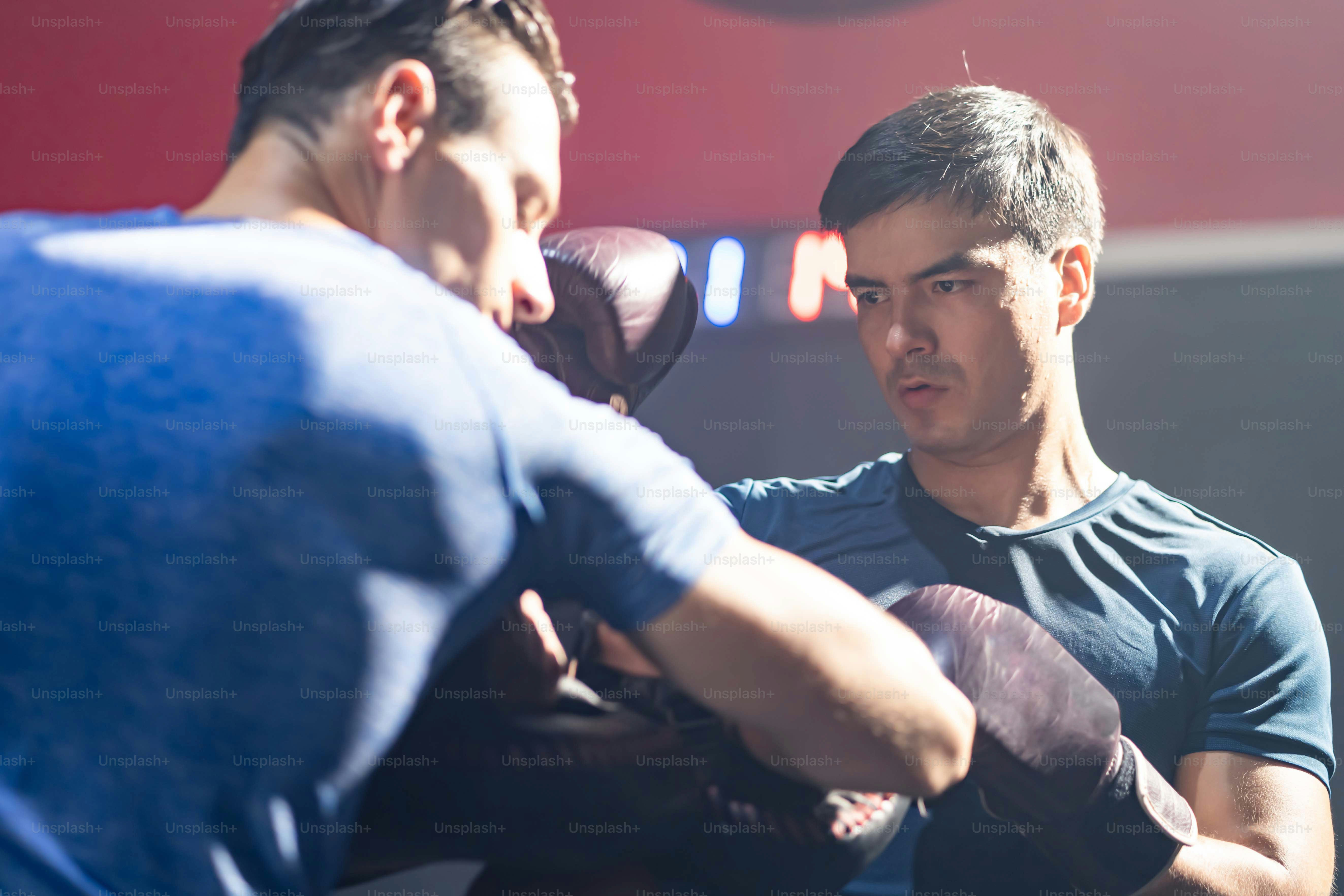 Istruttore di fitness caucasico insegnare e motivare il giovane pugile sportivo che si esercita facendo boxe o Muay Thai. Atleta combattente in guantone da boxe che pratica il pugno all'insegnante di allenamento al fitness o alla palestra.